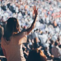 One person with hand raised in front of an audience